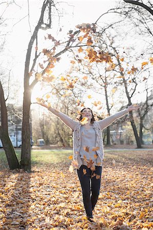 Mature woman throwing autumn dry leaves in air in the park, Bavaria, Germany Stock Photo - Premium Royalty-Free, Code: 6121-08660322