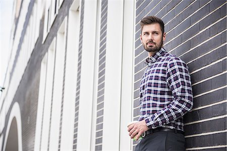 Young man leaning against wall and drinking coffee, Munich, Bavaria, Germany Photographie de stock - Premium Libres de Droits, Code: 6121-08859020