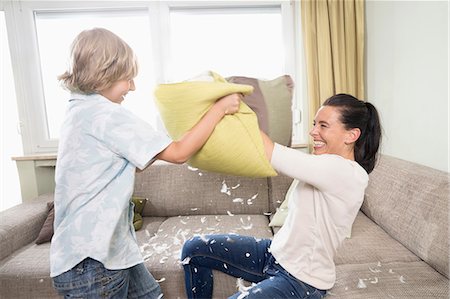 pluma - Woman pillow fighting with her son in living room, Bavaria, Germany Foto de stock - Sin royalties Premium, Código: 6121-08859188