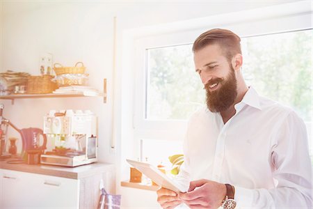 Young man using digital tablet in the kitchen, Bavaria, Germany Foto de stock - Sin royalties Premium, Código: 6121-08859311