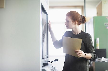 expert (female) - Young woman holding document and looking through glass window Stock Photo - Premium Royalty-Free, Code: 6121-08972551