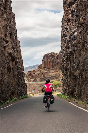 Rear view of woman riding electric bicycle on road amidst mountains Photographie de stock - Premium Libres de Droits, Code: 6121-08972694