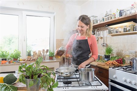 Young woman cooking food in kitchen Photographie de stock - Premium Libres de Droits, Code: 6121-09062224