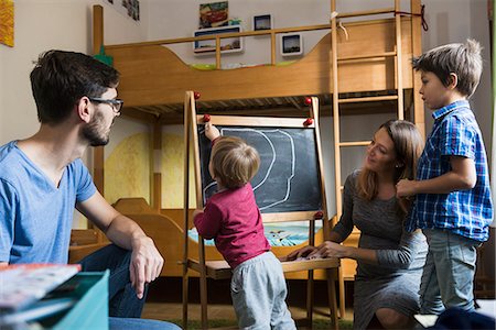 Little boy is writing on a blackboard, parents and the older brother are watching, Munich, Germany Stock Photo - Premium Royalty-Free, Code: 6121-09147047