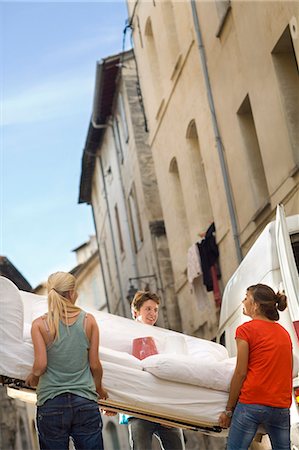 person standing back building street - Friends move couch in street Stock Photo - Premium Royalty-Free, Code: 6122-07691822