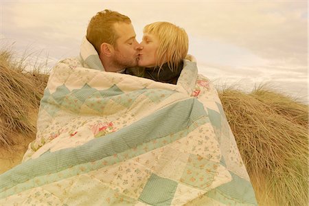 person wrapped in a blanket - Couple kissing under blanket on beach Stock Photo - Premium Royalty-Free, Code: 6122-07692369