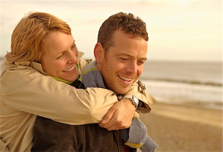 simsearch:6122-07691788,k - Woman embracing man from behind on beach Photographie de stock - Premium Libres de Droits, Code: 6122-07692374