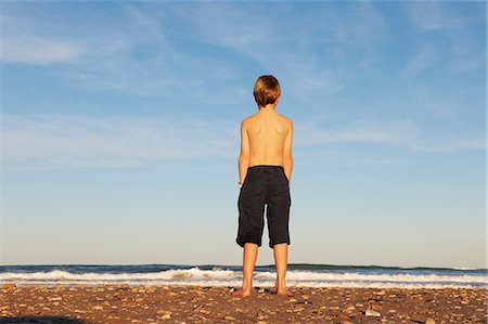 simsearch:6124-08658135,k - Boy on beach looking out to sea Stock Photo - Premium Royalty-Free, Code: 6122-07692649