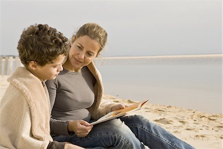 enseñar a los hijos - Mother and son reading book at the beach Foto de stock - Sin royalties Premium, Código: 6122-07692950