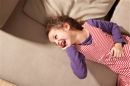 simsearch:6122-07703518,k - Little girl lying on couch laughing Photographie de stock - Premium Libres de Droits, Code: 6122-07693905