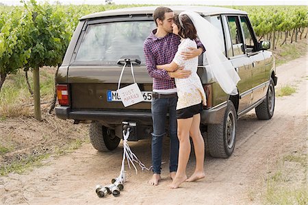 Newlywed couple kissing by vehicle Stock Photo - Premium Royalty-Free, Code: 6122-07694100