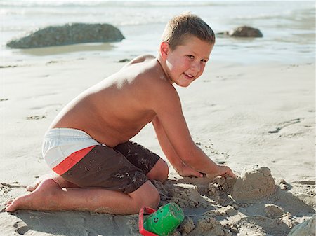 Boy making sandcastles on a beach Stock Photo - Premium Royalty-Free, Code: 6122-07694575