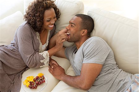 relaxing in couch black male - Woman feeding grapes to boyfriend Stock Photo - Premium Royalty-Free, Code: 6122-07695595