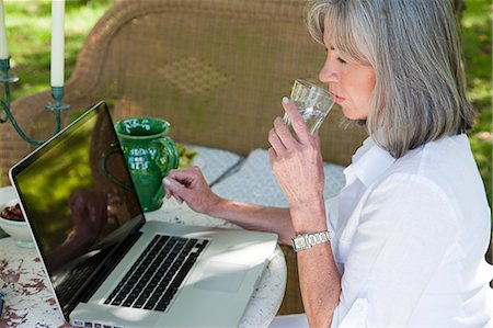 simsearch:614-03697410,k - Mature woman using laptop drinking water Stock Photo - Premium Royalty-Free, Code: 6122-07695648