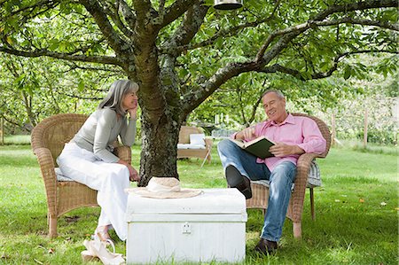 Mature couple outdoors, man reading book Stock Photo - Premium Royalty-Free, Code: 6122-07695662