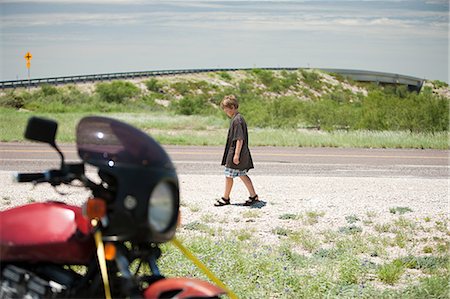 simsearch:6122-07695038,k - Boy walking past motorbike Foto de stock - Royalty Free Premium, Número: 6122-07695772