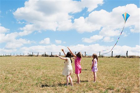 Three girls flying kite in field Stock Photo - Premium Royalty-Free, Code: 6122-07696741
