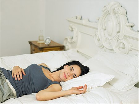 Young woman lying on bed Stock Photo - Premium Royalty-Free, Code: 6122-07696764