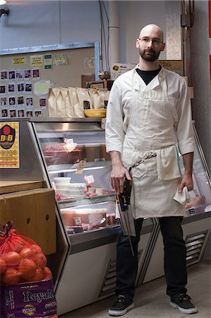 Butcher by counter of shop Fotografie stock - Premium Royalty-Free, Codice: 6122-07696808