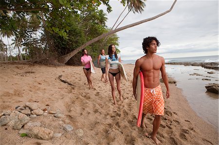 puerto rico people - Four young friends carrying surfboards on beach Stock Photo - Premium Royalty-Free, Code: 6122-07696941