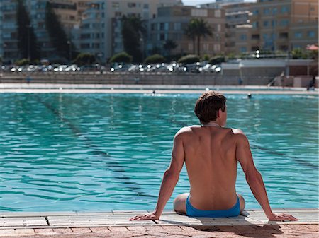 simsearch:6122-07694575,k - Young man sitting at poolside Stock Photo - Premium Royalty-Free, Code: 6122-07696973