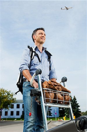 pasajero (hombre) - Mid adult man pushing luggage trolley at airport Foto de stock - Sin royalties Premium, Código: 6122-07697663