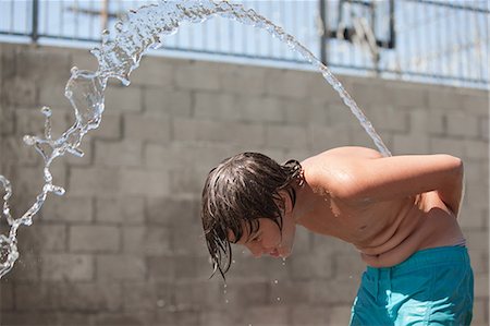 Boy squirting water over his back Stock Photo - Premium Royalty-Free, Code: 6122-07697603