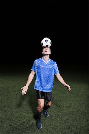 simsearch:6122-07697777,k - Young man heading soccer ball on pitch Photographie de stock - Premium Libres de Droits, Code: 6122-07697767