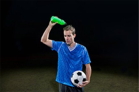 simsearch:6122-07697777,k - Young soccer player pouring water of himself on pitch Photographie de stock - Premium Libres de Droits, Code: 6122-07697769