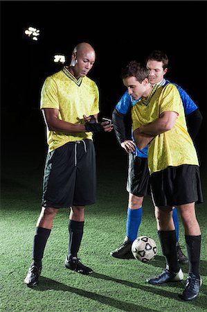 simsearch:6122-07697777,k - Soccer players looking at cellphone on pitch Photographie de stock - Premium Libres de Droits, Code: 6122-07697773