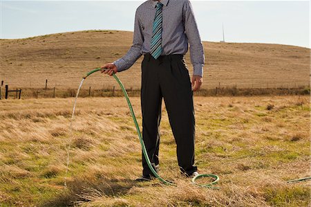 scarcity - Man holding hose pipe in arid landscape Stock Photo - Premium Royalty-Free, Code: 6122-07697708