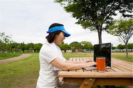 simsearch:6122-07698450,k - Woman using laptop on picnic bench in the park Photographie de stock - Premium Libres de Droits, Code: 6122-07698450