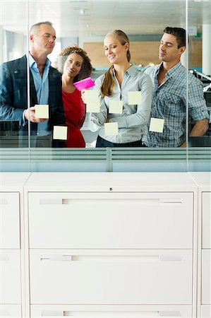 Office colleagues arranging adhesive notes on office window Foto de stock - Sin royalties Premium, Código: 6122-07698414