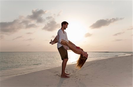 Couple playing on beach at sunset Photographie de stock - Premium Libres de Droits, Code: 6122-07699034