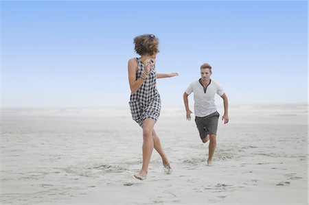 Couple chasing each other on beach Stock Photo - Premium Royalty-Free, Code: 6122-07699391