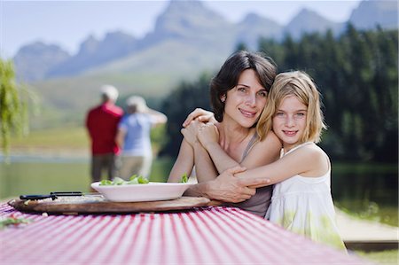 simsearch:6113-07159602,k - Mother and daughter hugging at picnic Photographie de stock - Premium Libres de Droits, Code: 6122-07699466