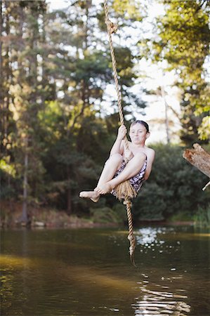 dondolamento ad un albero - Young girl using rope swing over lake Fotografie stock - Premium Royalty-Free, Codice: 6122-07699490