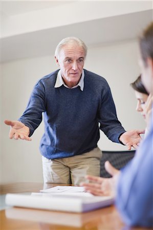 persuasion - Businessman shrugging in meeting Stock Photo - Premium Royalty-Free, Code: 6122-07699411