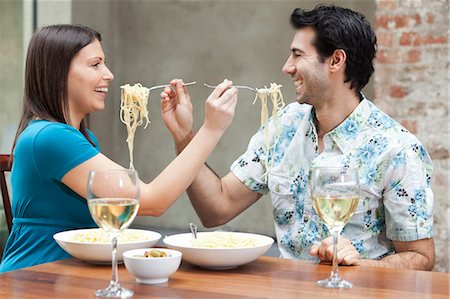 photo of a woman feeding her husband food - Couple feeding each other spaghetti Stock Photo - Premium Royalty-Free, Code: 6122-07699507