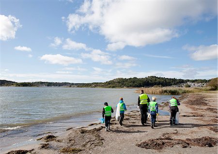 people holding garbage bags - Boys in safety vests cleaning beach Stock Photo - Premium Royalty-Free, Code: 6122-07699890