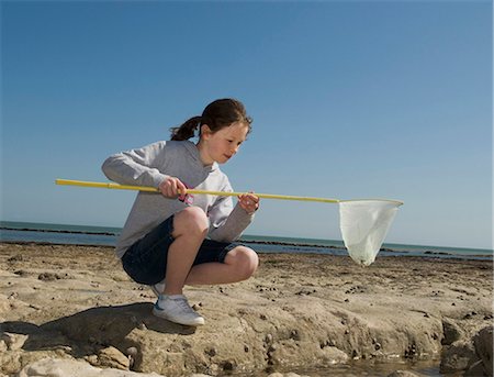 pozza di marea - Girl playing with fishing net on beach Fotografie stock - Premium Royalty-Free, Codice: 6122-07700059