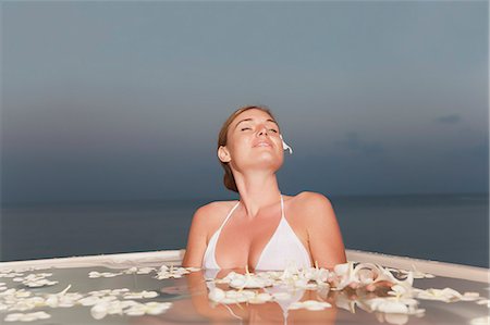 Woman sitting in pool with flowers Stock Photo - Premium Royalty-Free, Code: 6122-07700132