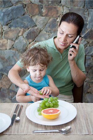 papa multitasking - Woman eating breakfast with son Stock Photo - Premium Royalty-Free, Code: 6122-07701100