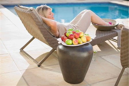 simsearch:6113-07731619,k - Woman relaxing in lawn chair by pool Photographie de stock - Premium Libres de Droits, Code: 6122-07701435