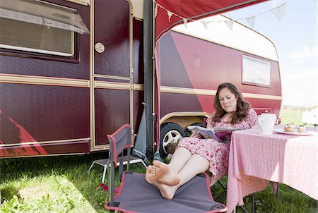 Woman reading magazine outside trailer Stock Photo - Premium Royalty-Free, Code: 6122-07702412