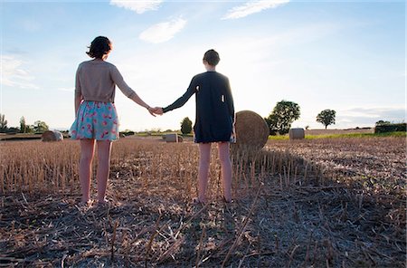 Girls holding hands in hay field Stock Photo - Premium Royalty-Free, Code: 6122-07702500