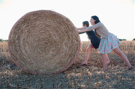 rolled up (clothing) - Girls pushing hay bale in field Stock Photo - Premium Royalty-Free, Code: 6122-07702502