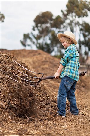 Boy using pitchfork in haystack Stock Photo - Premium Royalty-Free, Code: 6122-07702648