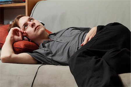 simsearch:400-07712720,k - Man listening to headphones on couch Stock Photo - Premium Royalty-Free, Code: 6122-07702680