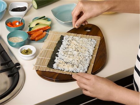 Woman preparing sushi roll at table Stock Photo - Premium Royalty-Free, Code: 6122-07702977